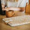 Offspring laptop case sitting on table next to woman with computer and mug